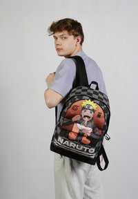 Zwart-grijs geblokte rugzak met een kleurraf Naruto-afbeelding, verstelbare schouderbanden en een voorzak met rits voor handige opbergruimte.