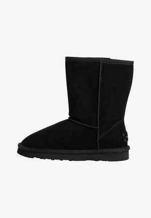 Schwarze Wildleder-Ankle-Boots mit runder Spitze, flacher Gummisohle und Nahtdetails. Mit einem Logo-Tag an der Seite für die Markenidentität.