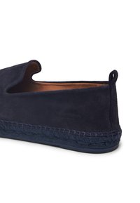 Zapato sin cordones de ante azul marino con detalles trenzados en la suela media y una cinta de tirón en el talón, visto de lado sobre un fondo blanco.
