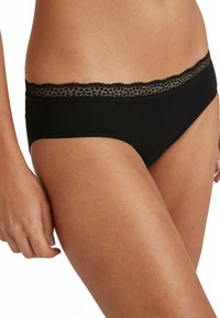 Black underwear featuring a delicate lace trim along the waistband, soft fabric texture, and fitted design that follows body contours.