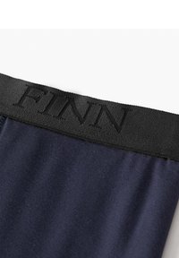 Marineblaue Baumwollleggings mit einem schwarzen elastischen Bund, der den geprägten Text "FINN" an der Oberseite trägt. Glatte Textur und taillierte Passform.