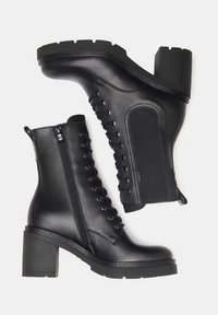 Stivaletti neri in pelle con tacco chunky, dotati di lacci frontali, zip laterale e pannello elastico accentuato per una maggiore flessibilità.