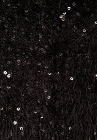 Svart texturerad tyg med fluffiga fibrer och spridda glittrande paljetter som skapar ett glittrande utseende. Jämnt fördelade dekorationer.