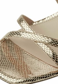 Gold metallic sandals with a cross-strap design, featuring a textured snake-skin pattern on the toe area and smooth inner lining.