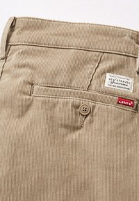 Beiga kordflöjtsbyxor med vertikala ränder, med en bakficka, knäppning med knapp och en Levi's-label på midjebandet.