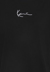 Černé bavlněné tričko s bílým vyšitým logem na hrudi. Design s kulatým výstřihem a krátkými rukávy, hladká textura.