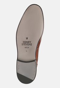 Sole di scarpa in pelle marrone con superficie piatta e liscia. Presenta il marchio impresso "HENRY STEVENS BERLIN", taglia 8, e rivetti in rame lungo il bordo.