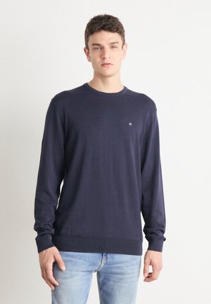 Marineblauwe crewneck trui met lange mouwen, gemaakt van zacht materiaal. Heeft een klein logo op de borst en ribgebreide manchetten en onderkant.