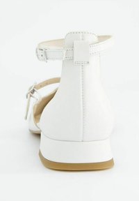 Sándalo de cuero blanco con tira en el tobillo, tacón bajo y textura suave. Presenta una punta redondeada y un diseño minimalista.