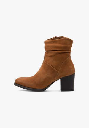 Brown suede ankle boot with a slouched design, pointed toe, and a chunky black heel. Features a zip closure on the back.
