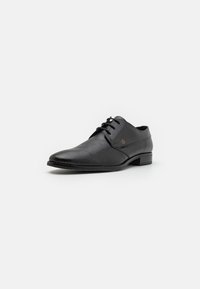 Scarpa da uomo in pelle nera con finitura texturizzata, punta rotonda e design con lacci. Presenta un discreto dettaglio del logo e un tacco basso.