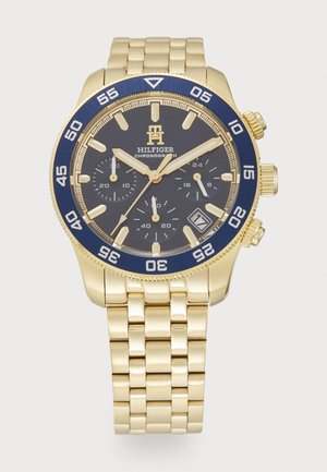 Gold-tone chronograph watch with a blue bezel, black dial, and three subdials. Features a metal bracelet and a date window at 4 o'clock.