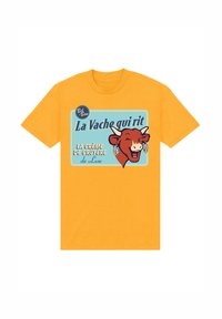 Žluté bavlněné tričko s grafikou usmívající se krávy s náušnicemi, text zní "La Vache qui rit" a "La crème de Gruyère de Luxe."