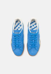 Sneakers blu in suede con suole bianche e strisce verdi lime. Include lacci blu e una fodera interna con il marchio Reebok.