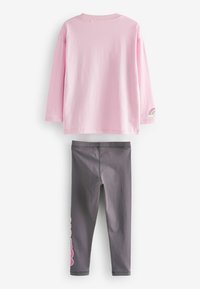 Rosa långärmad skjorta med regnbågsdetaljer på ärmen, tillsammans med grå leggings med rosa text längs sidan. Tillverkat av bomull.