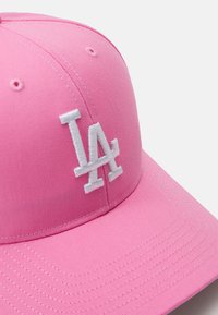 Rosa Baseballmütze aus Stoff mit strukturiertem Design. verfügt über ein weiß gesticktes "LA"-Logo und eine subtile Textur auf der Krone und dem Schirm.