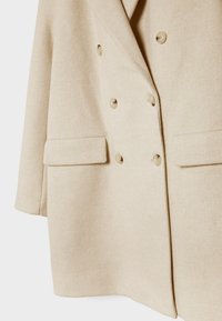 Beige double-breasted wool-blend blazer featuring two front pockets, large buttons, and a textured fabric. Tailored fit with structured shoulders.
