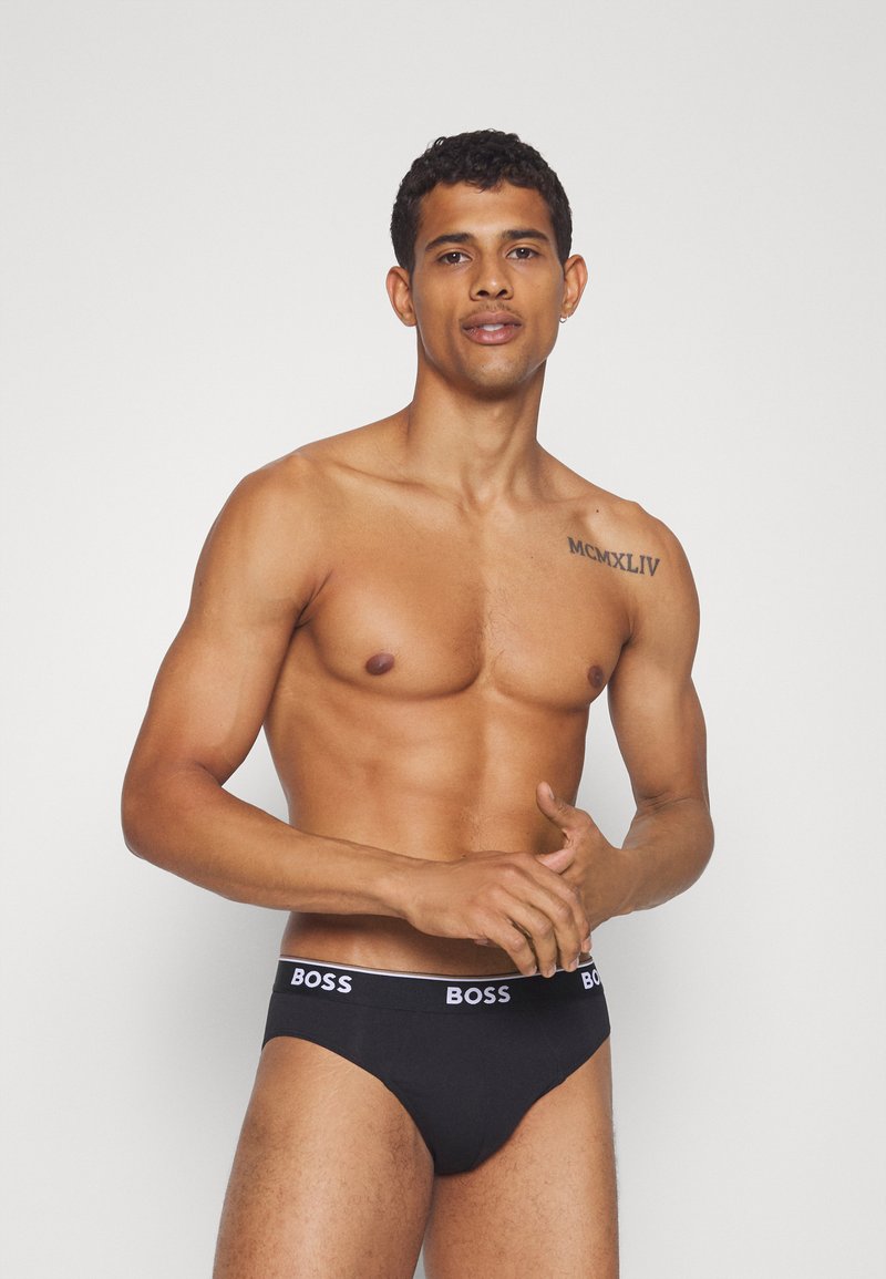 Culottes en coton noir avec un logo "BOSS" blanc sur la ceinture, offrant une texture lisse et un design minimaliste.