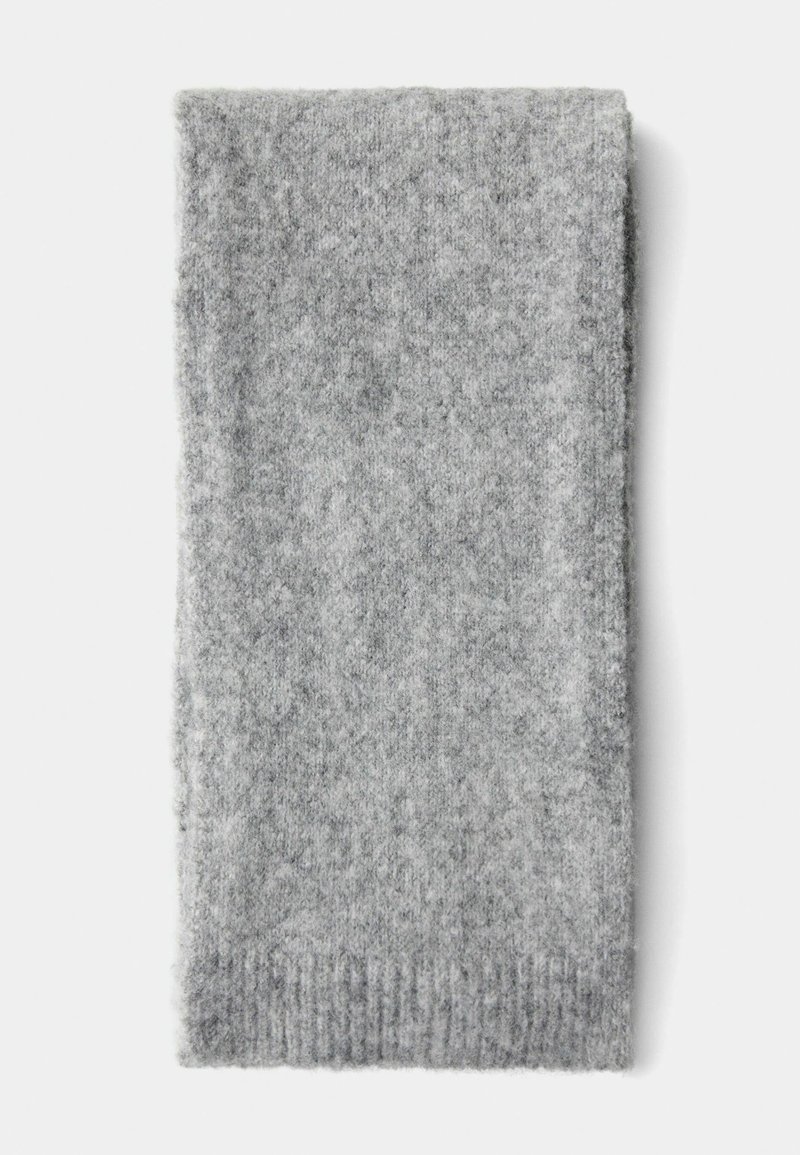 Écharpe en tricot grise avec une finition douce et texturée. Présente un bord côtelé à une extrémité. Forme rectangulaire, sans motifs ou accents distincts.