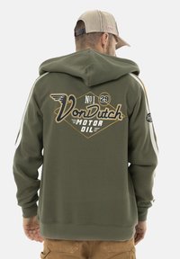 Hoodie vert olive avec un grand graphisme "VonDutch Motor Oil" en blanc et or au dos. Équipé d'une capuche et de bandes blanches sur les côtés.