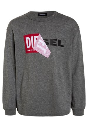 Grijze Diesel-sweatshirt met zwarte tekst en een rode patch die deels bedekt is door een gevouwen roze stoffen vierkant op de borst.