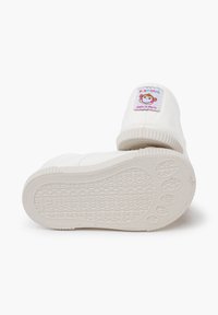Weiße Leinenschlupfschuhe mit strukturierten Gummisohlen, versehen mit einem bunten Affen-Patch an der Ferse und gerippten Akzenten am Öffnung.