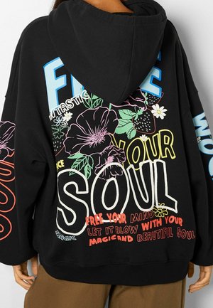 Sweat à capuche noir avec des motifs floraux et de fraises colorés, avec un texte en gras « SOUL » et des phrases comme « Libère ton esprit » et « Belle âme » dans le dos.