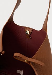 Brown leather shoulder bag with burgundy interior, gold magnetic clasp, and a small leather strap detail inside.