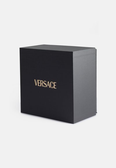 Caja rectangular negra con un acabado texturizado y el logo dorado "VERSACE" en la parte frontal. Sin hardware ni acentos visibles. Diseño simple y elegante.