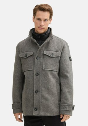 Grau melierte Wollmischjacke mit hohem Kragen, zwei Brusttaschen, sechs Knöpfen und schwarzen Akzenten. Verfügt über eine strukturierte Oberfläche und eine robuste Konstruktion.