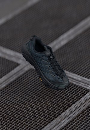 Scarpa da trekking nera con tomaia testurizzata, punta rinforzata e sistema di allacciatura. Presenta una suola Vibram per trazione e durata.