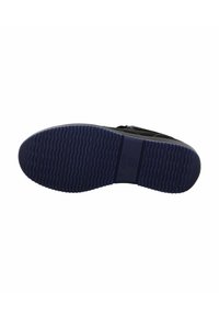 Zapato negro tipo slip-on con una superficie texturizada, que cuenta con una suela de goma azul gruesa con un patrón estriado paralelo y un logotipo en el costado.