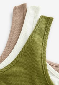Trois débardeurs côtelés dans des tons terreux : marron, blanc et vert olive, présentant un tissu texturé et des coutures contrastantes le long des bords.