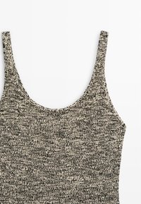 Débardeur en tricot noir et blanc avec fines bretelles et encolure dégagée, présenté sur un fond blanc uni.