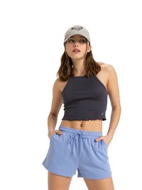 Top court côtelé gris foncé avec un ourlet en scallop associé à un short à cordon de serrage bleu clair. Le mannequin porte une casquette grise avec un logo brodé.