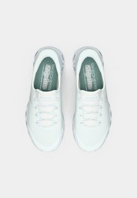 Λευκά παπούτσια χωρίς κορδόνια με αεριζόμενο επάνω μέρος από δίχτυ, ελαστικά κορδόνια και υφή στη σόλα. Διαθέτουν μαλακό πάτο για άνεση.