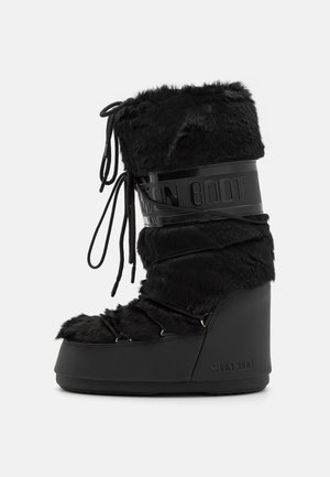 Čierne Moon Boot s umelou kožušinou, nastaviteľné šnúrky a hrubá platformová podrážka. Obsahuje lesklý čierny pás s detailom loga.