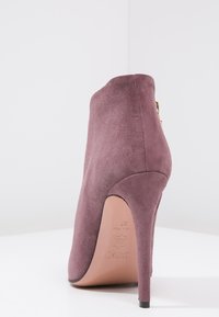 Zamszowe botki za kostkę w kolorze mauve, o smukłym, zwężającym się kroju, z wysokim obcasem w szpilce i złotym zamkiem na boku. Gładka faktura.