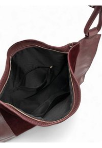 Sac en cuir bordeaux avec fermeture éclair, intérieur en tissu noir et une poche intérieure pour une meilleure organisation. Texturé lisse et forme structurée.