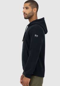 Marineblauwe hoodie met een voorzak, trekkoordsluiting en logo-detail op de linker mouw. Zacht materiaal en ribgebreide manchetten.