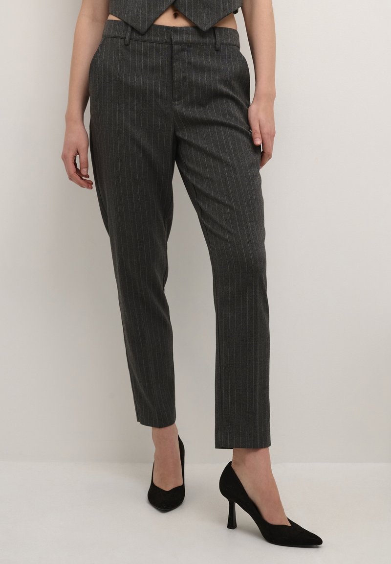 Pantalon gris à fines rayures, coupe ajustée, taille mi-haute et longueur raccourcie, associé à des escarpins noirs à bout pointu.