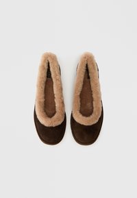 Pruunist nahaefektiga sussid, millel on pehme beež kunstkarv vooder avamisel ja taldades, tasase tallaga ja ümarate servadega.