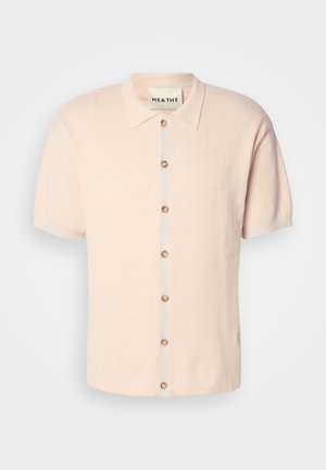 Camicia a maniche corte con colletto di un rosa pallido, caratterizzata da un motivo texturizzato, chiusura frontale a bottoni tondi e un dettaglio del logo sull'orlo.