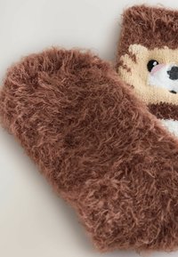 Bruna fluffiga tygsockor med en söt djurdesign, mjuk textur och rund form med framträdande, fluffiga detaljer.