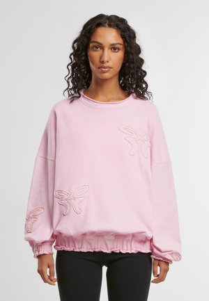 Sweat-shirt rose clair avec un ourlet volanté et une coupe oversize. Présente des détails en broderie de papillons sur le devant, des manches longues et un col rond.