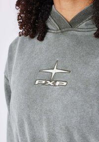 Grijze hoodie met een gestructureerde afwerking heeft een geborduurd "PXP" logo in zilver op de borst en een ribbel detail op de hals.
