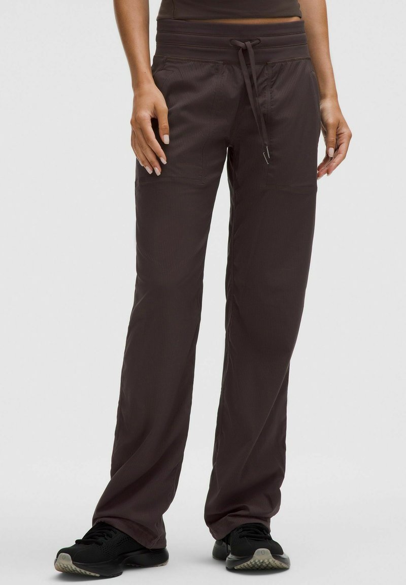 Pantaloni activi maroni cu talie elastică, șnur și două buzunare laterale. Construiți dintr-un material ușor, texturat. Potriviți pentru exerciții fizice.