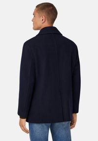 Marineblaue Wollmischungsoverall mit Reverskragen, langen Ärmeln und geradem Schnitt. Verfügt über eine Rückennaht und ein minimalistisches Design.