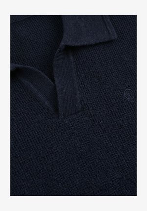 Mørk marineblå strikket polokrave med vaffelstruktur og subtilt broderet logo på brystet.