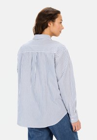 Gestreiftes Button-up-Hemd mit blauen und weißen vertikalen Streifen, langen Ärmeln, klassischem Kragen und einem lockeren Schnitt mit abgerundetem Saum.